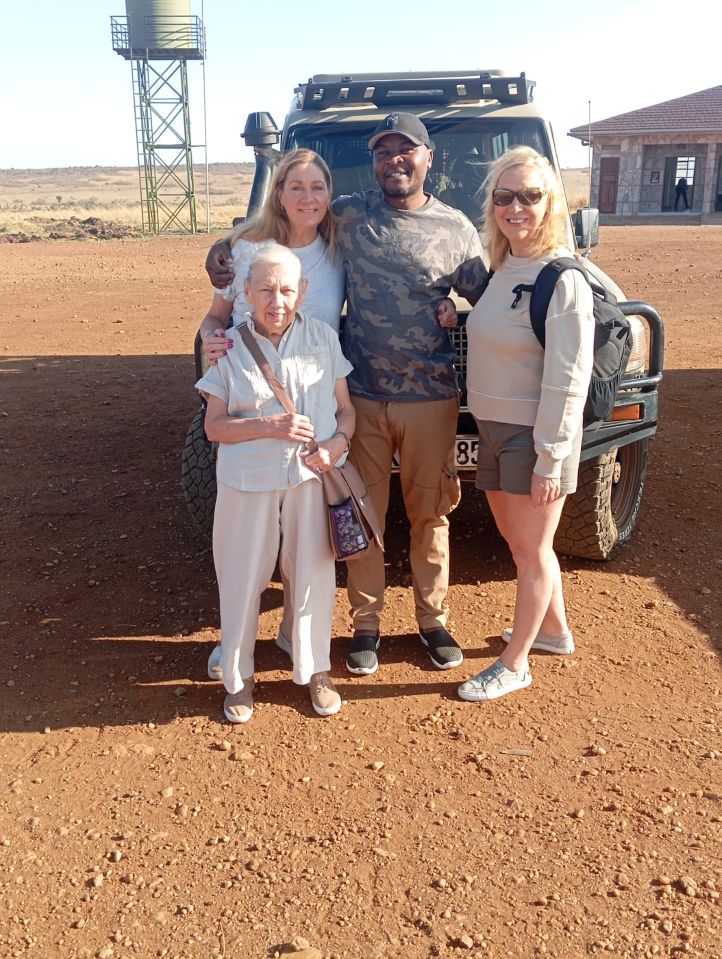 Safari guide welcoming guests beside a Toyota Land Cruiser at the airport